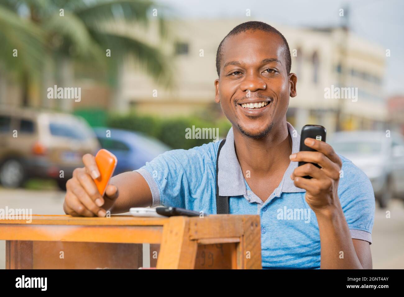 homme souriant assis à une cabine téléphonique Foto Stock