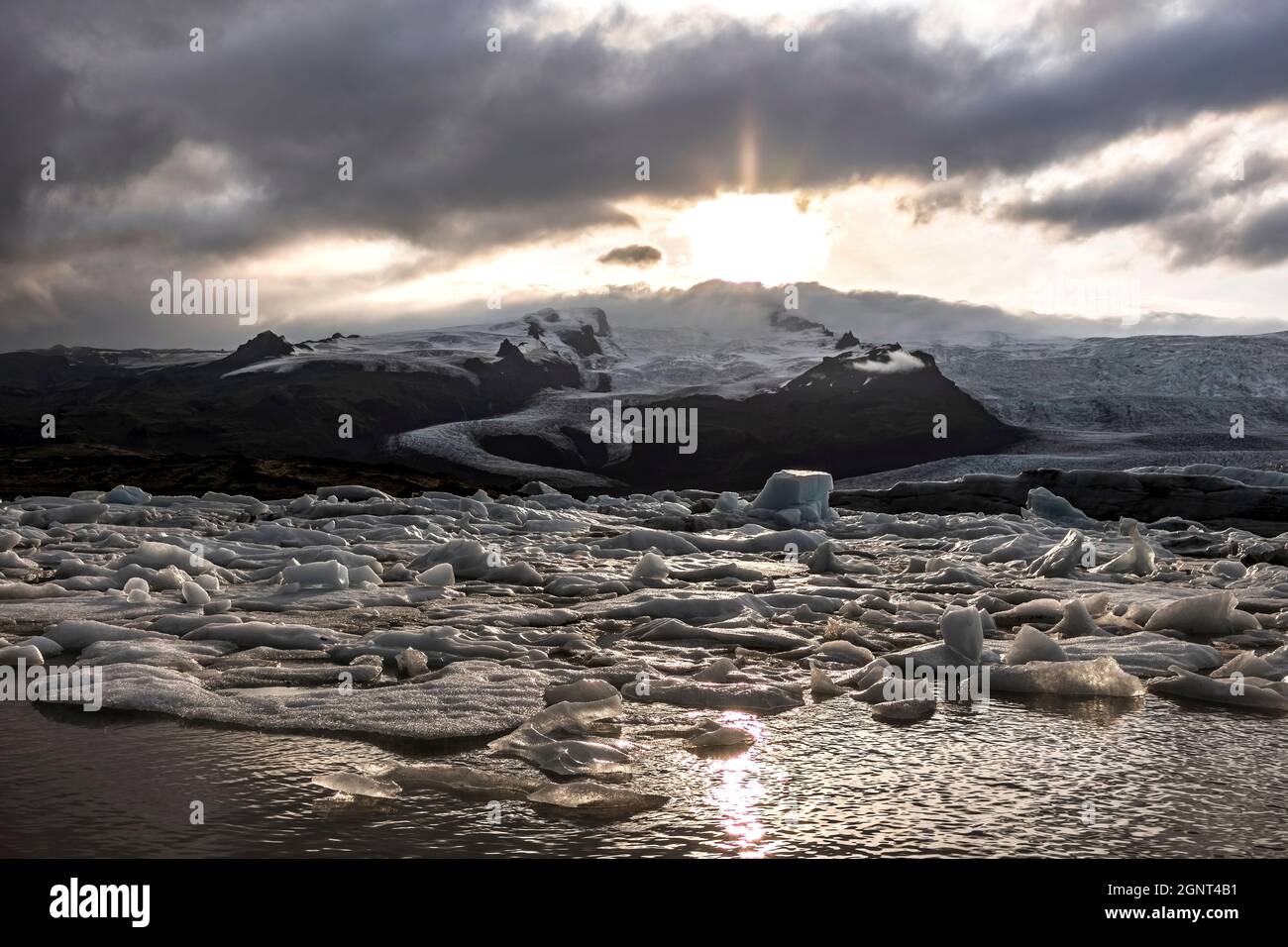 Ghiaccioli galleggianti su un lago durante un tramonto drammatico a Fjallsárlón. Fjallsárlón, un lago ghiacciato all'estremità sud del ghiacciaio islandese Vatnajökull Foto Stock