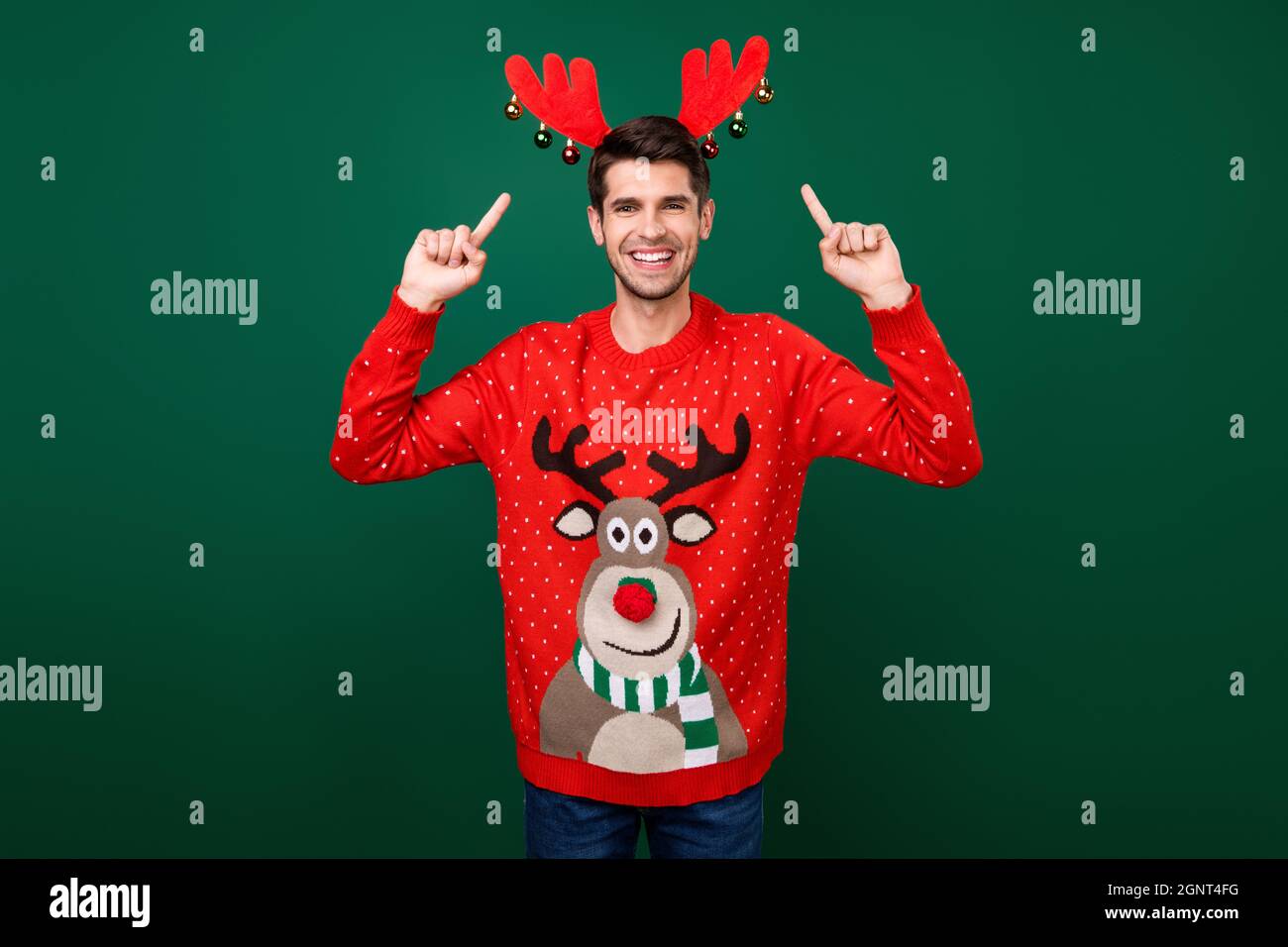 Foto di giovane uomo felice positivo sorriso punto dito cerchietto renna  corna nuovo anno spirito isolato su sfondo verde colore Foto stock - Alamy