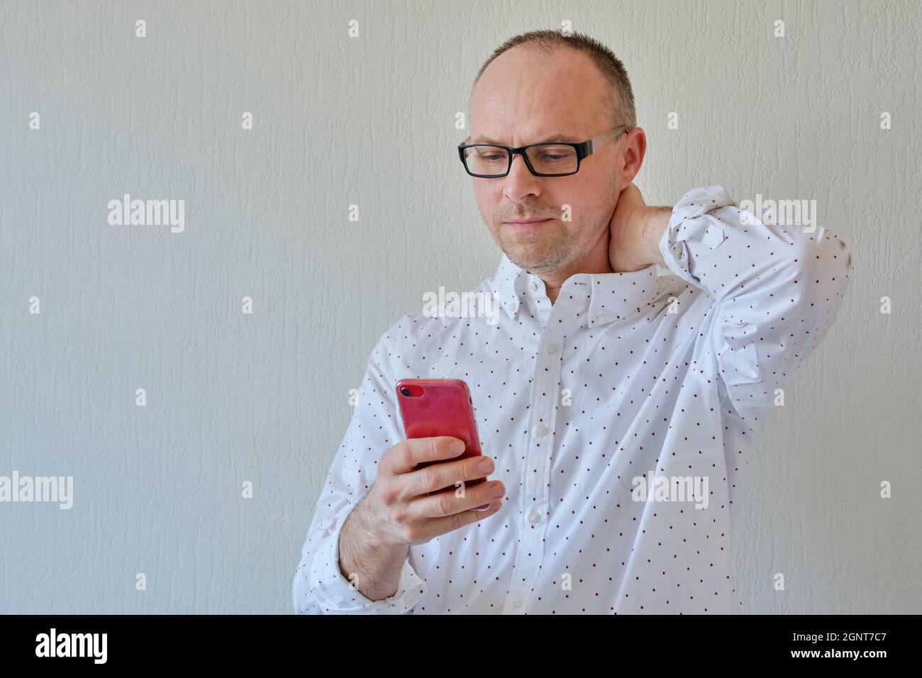Visualizzazione a metà lunghezza di un uomo con uno smartphone. Sfondo bianco con spazio per testo o annotazioni. Bell'uomo guarda il suo telefono. Foto Stock