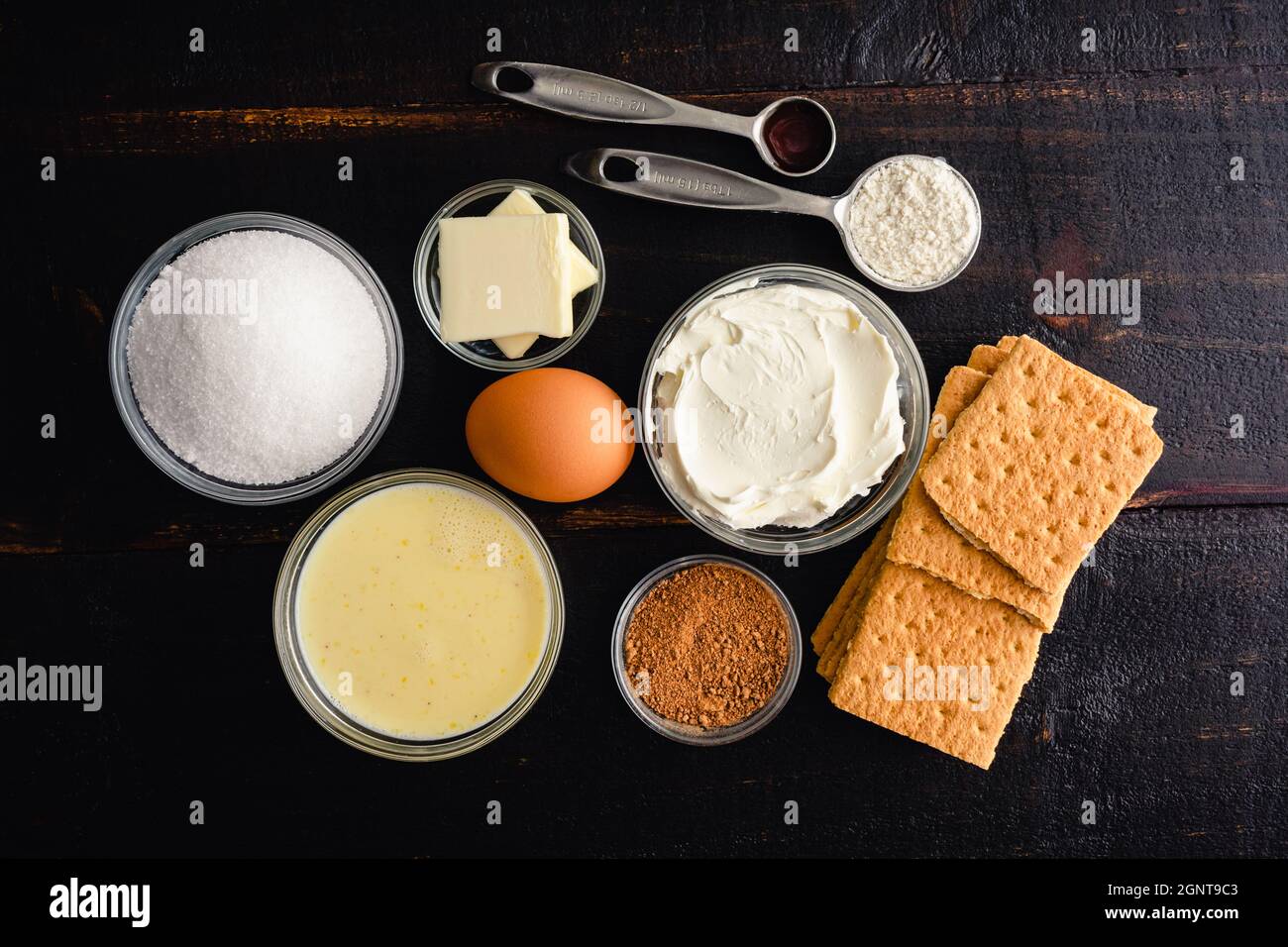 Mini Eggnog Cheesecake ingredienti: Eggnog, formaggio spalmabile e altri ingredienti per cupcake eggnog su sfondo di legno Foto Stock