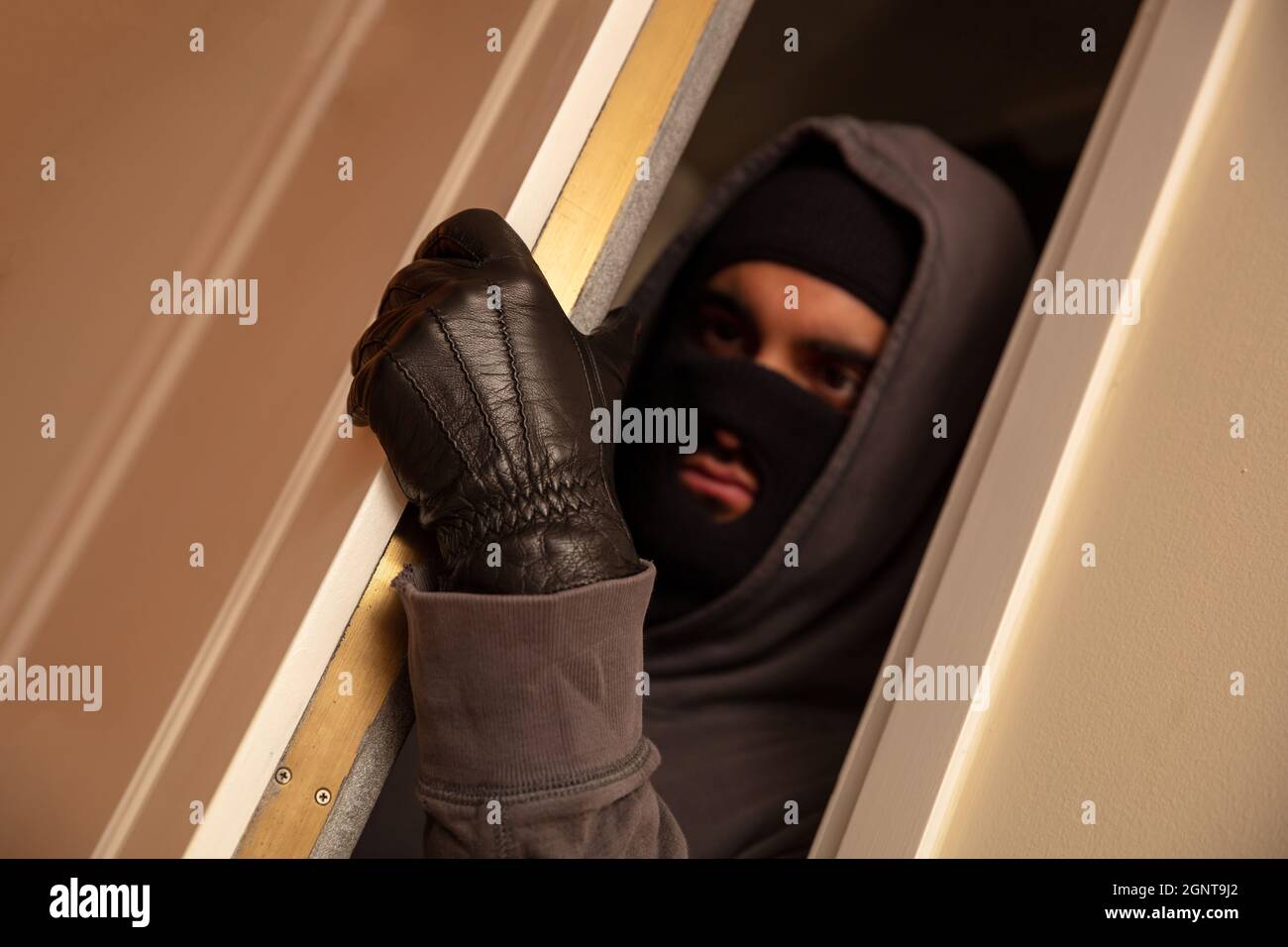 Housebreaking, burglary concetto. Mascherato burglar in balaclava nera aprendo la porta, entrando illegalmente la casa Foto Stock