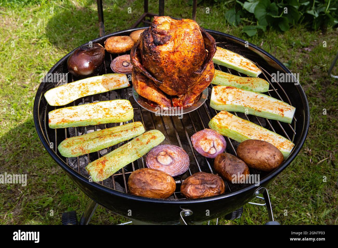 Carcassa di pollo e verdure cotte e affumicate su una griglia a carbone Foto Stock