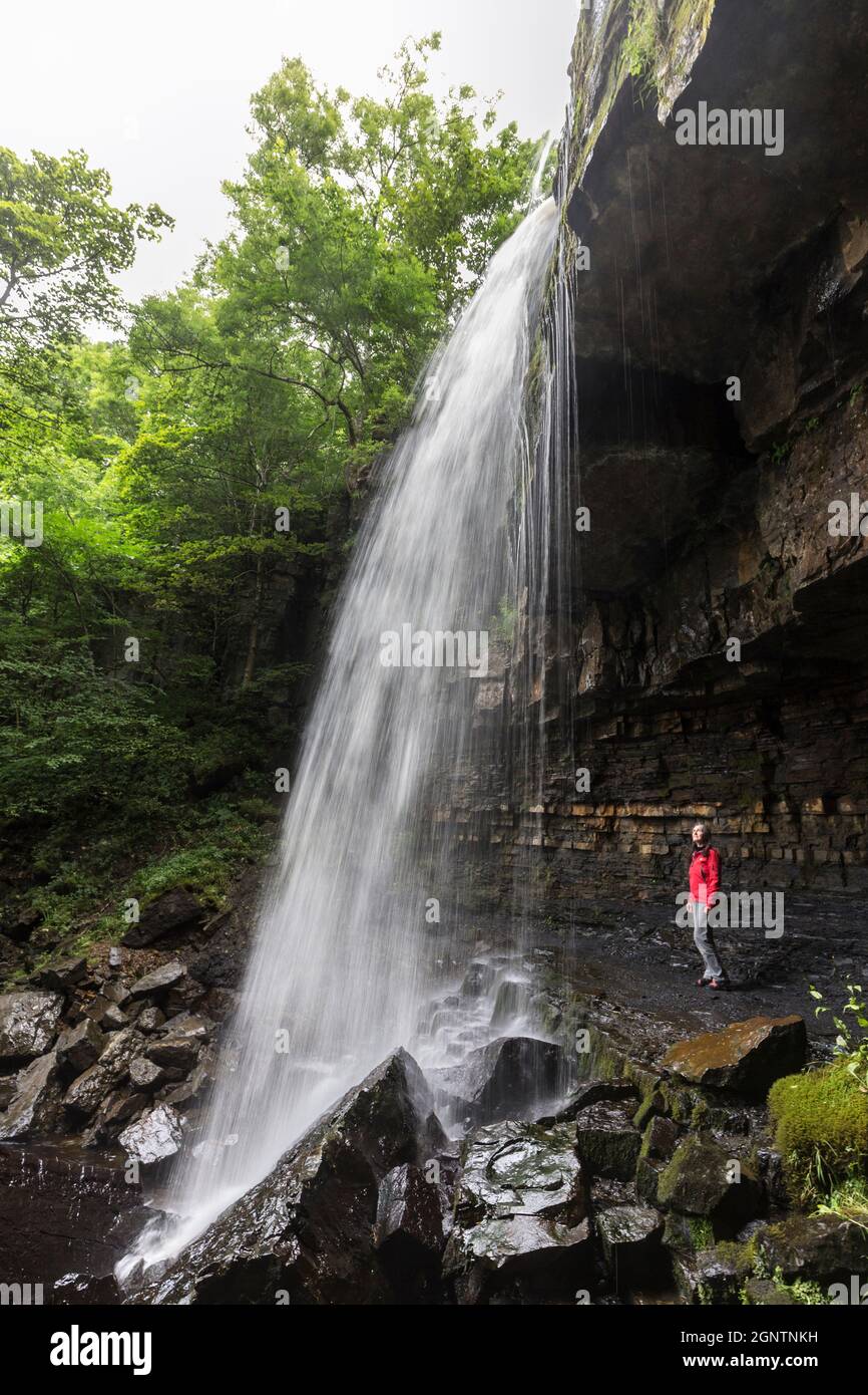 Persona in piedi dietro Ashgill Force Waterfall, Alston, Cumbria, Regno Unito Foto Stock