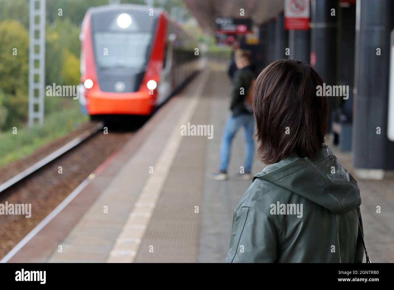 Persone in attesa del treno in arrivo sulla stazione ferroviaria. Passeggeri del treno pendolari in autunno Foto Stock
