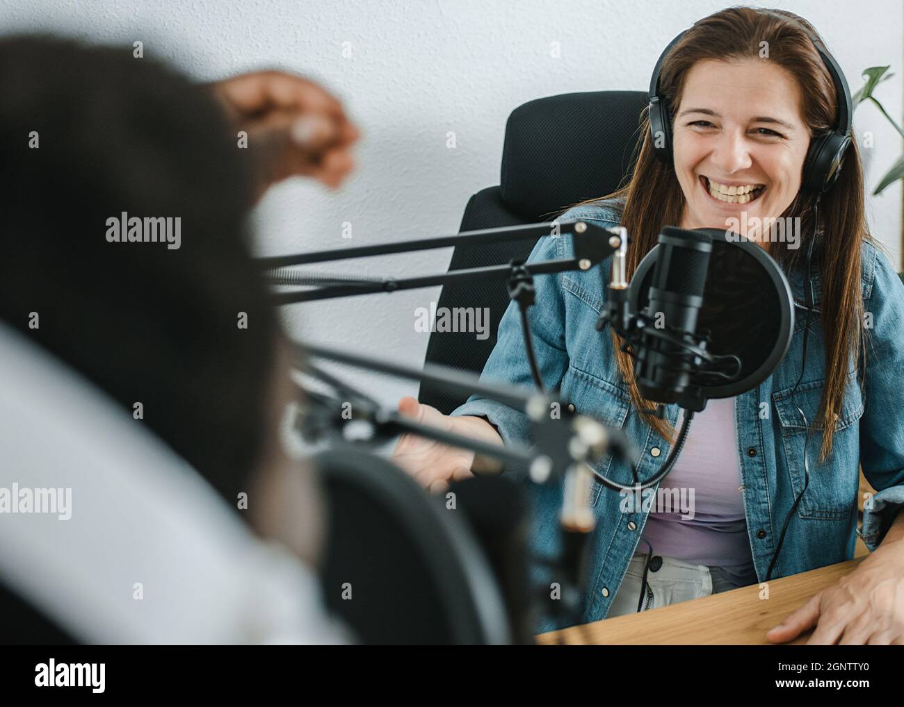 Felice donna che registra podcast con crop black man Foto Stock