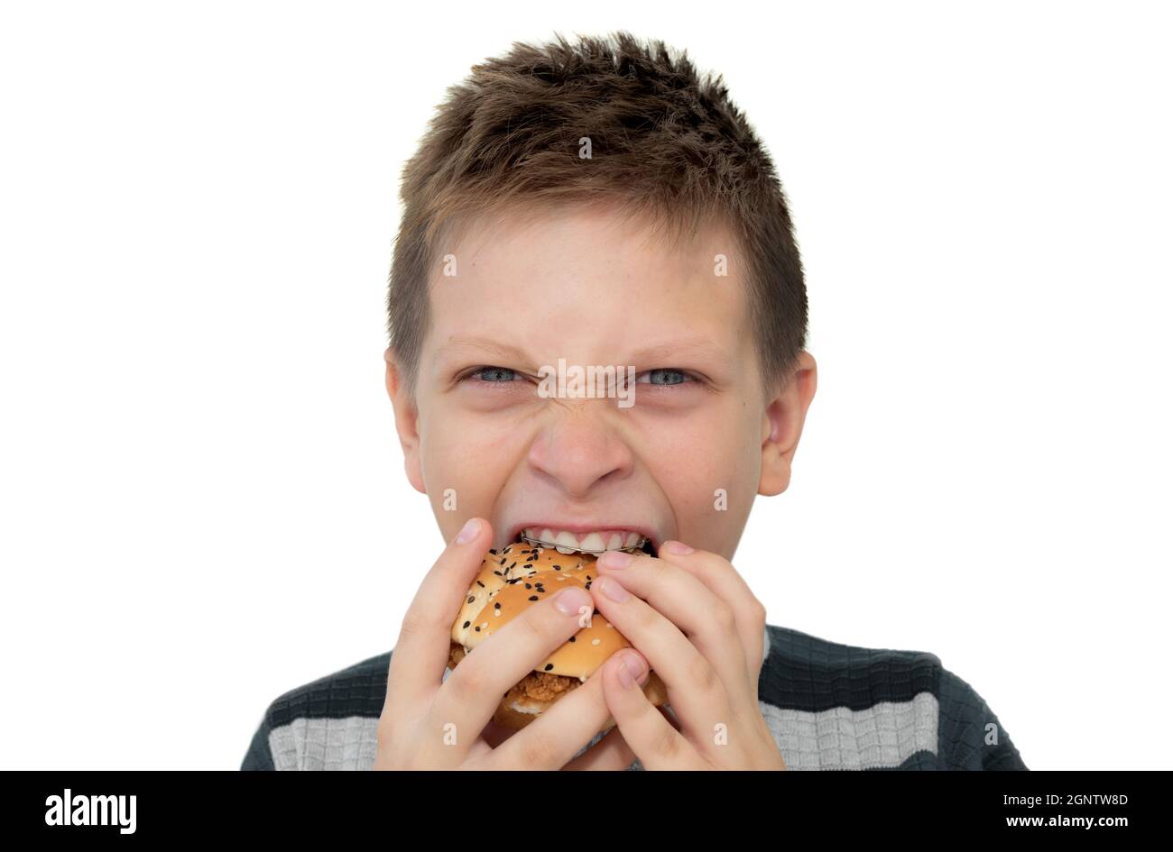 Ragazzo che mangia hamburger su sfondo bianco. Adolescente in bretelle. Cibo dannoso per i bambini Foto Stock