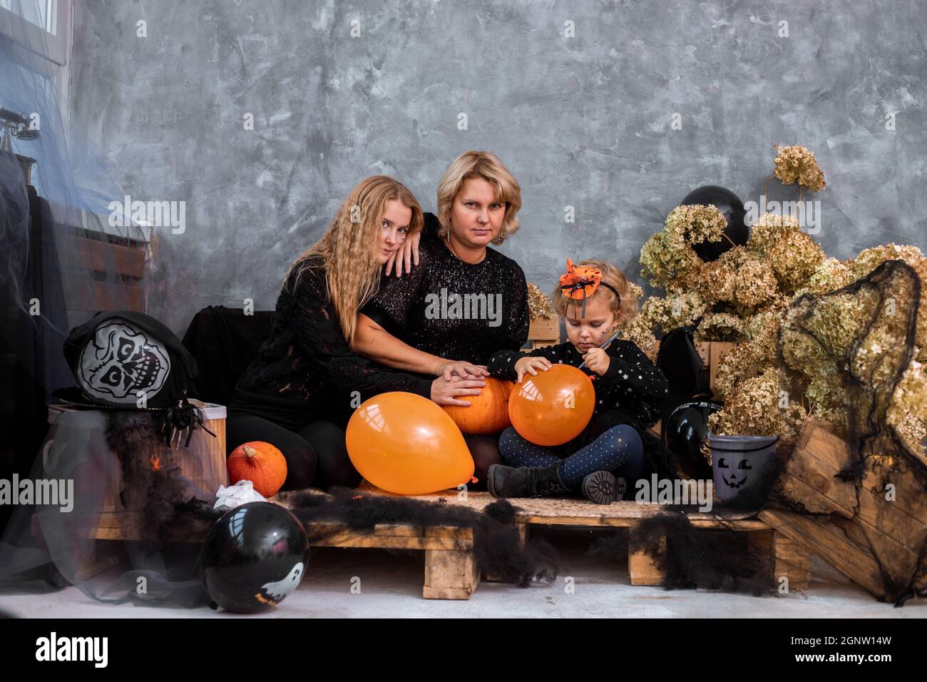 Mamma con i bambini due ragazze e figlie tra decor con toni arancione e nero per Halloween hanno divertimento e spendere Foto Stock