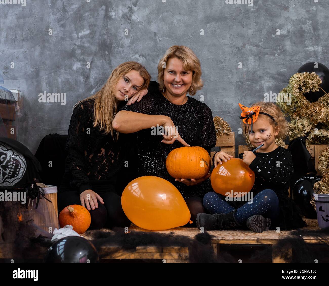 Mamma con i bambini due ragazze e figlie tra decor con toni arancione e nero per Halloween hanno divertimento e passare il tempo insieme Foto Stock