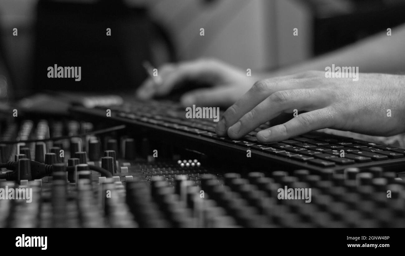 Primo piano delle mani su una tastiera su una console di mixaggio. Foto Stock