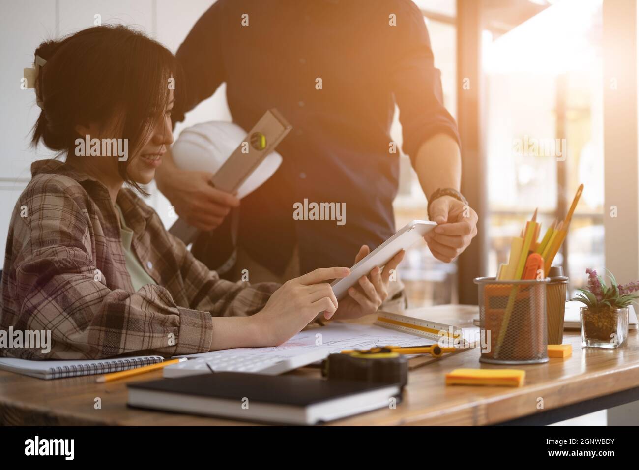 Due colleghi discutono dei dati che lavorano con il tablet digitale per progetti architettonici presso il cantiere presso la scrivania dell'ufficio. Foto Stock