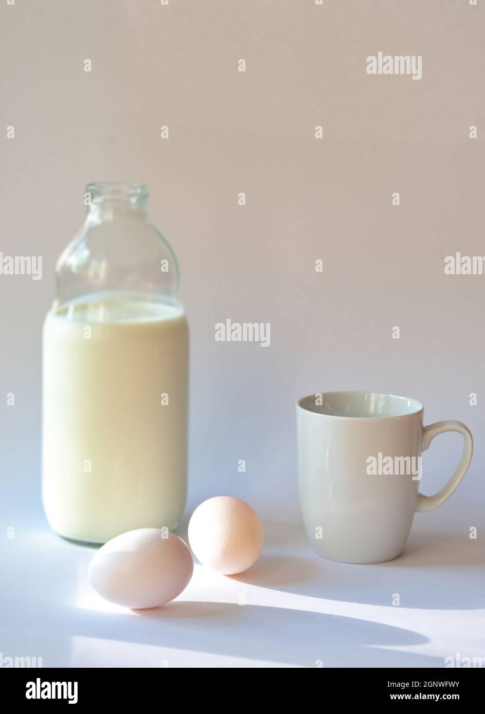 Bottiglia con latte, tazza di caffè e uova su sfondo bianco Foto Stock