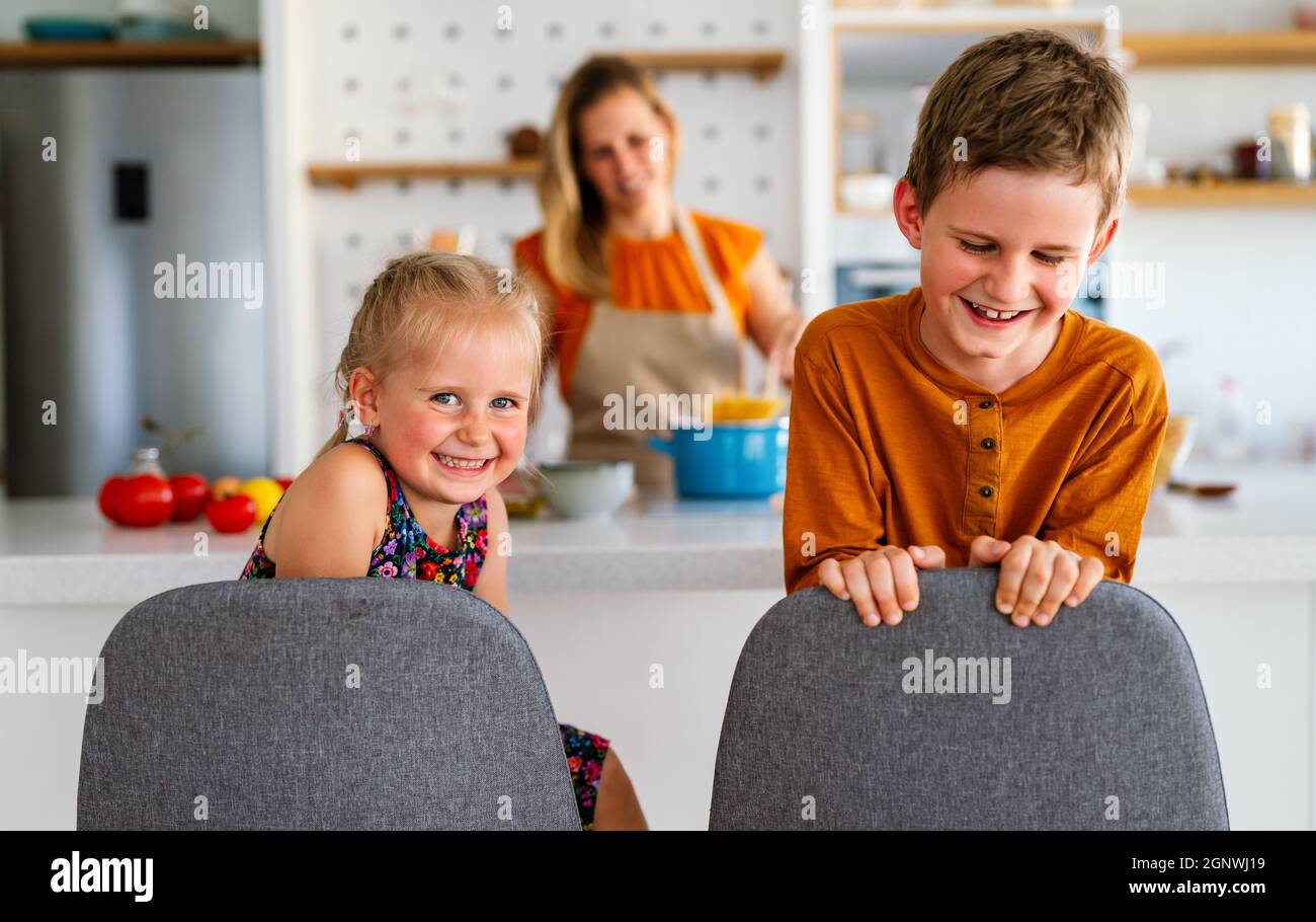 Famiglia felice a casa. Madre e bambini in cucina. Carino piccolo aiutante. Foto Stock