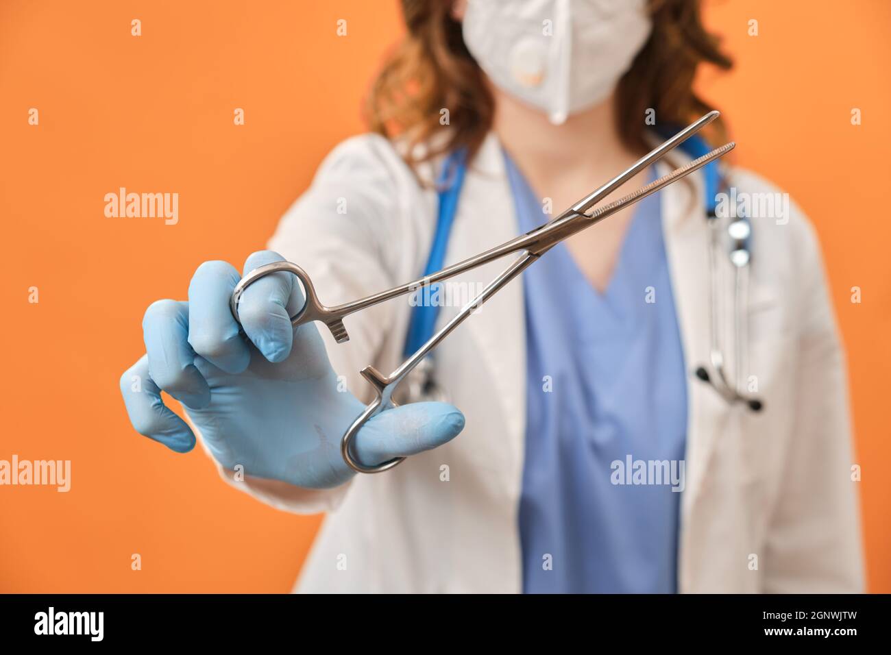 Il medico tiene in mano un morsetto chirurgico. Infermiera con una clip  medica con le forbici in mano, sfondo studio Foto stock - Alamy