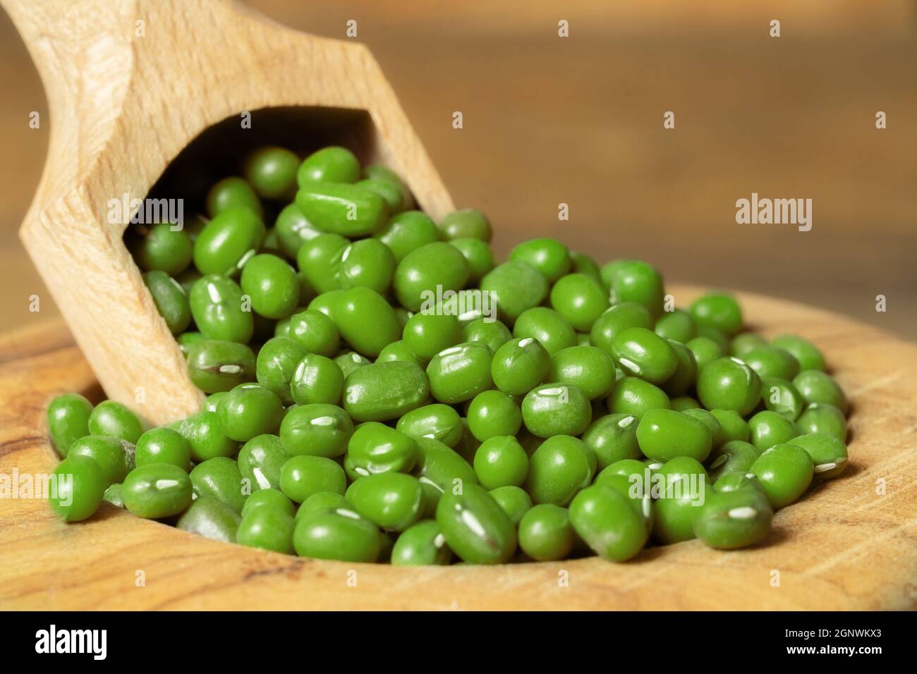 Primo piano di fagioli di soja in una ciotola con un cucchiaio. Piselli verdi secchi in una ciotola di legno su sfondo di legno. Foto Stock