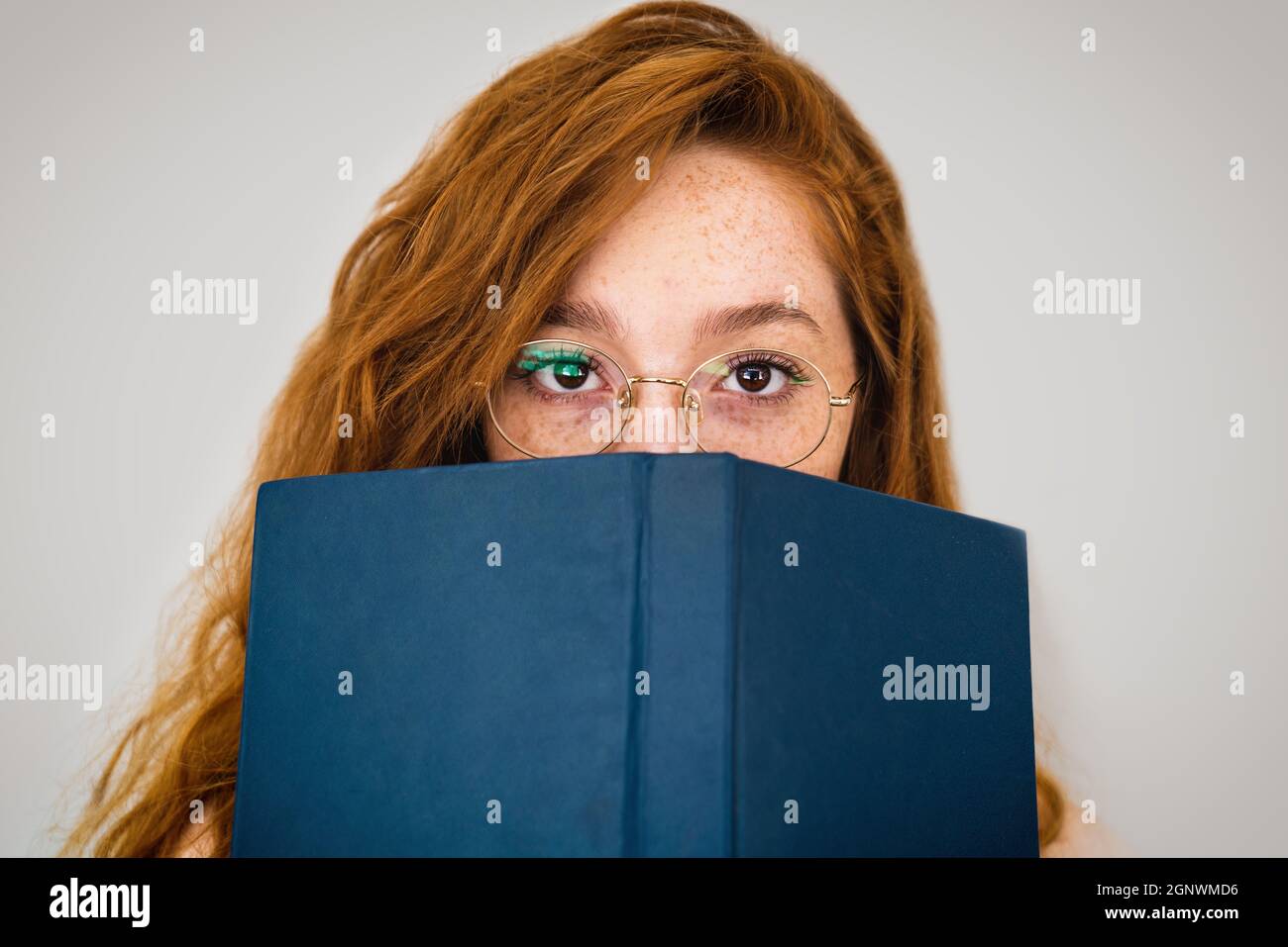 Primo piano di una giovane donna intellettuale con un libro di fronte al suo volto. Alfabetizzazione concetto. Foto di alta qualità Foto Stock