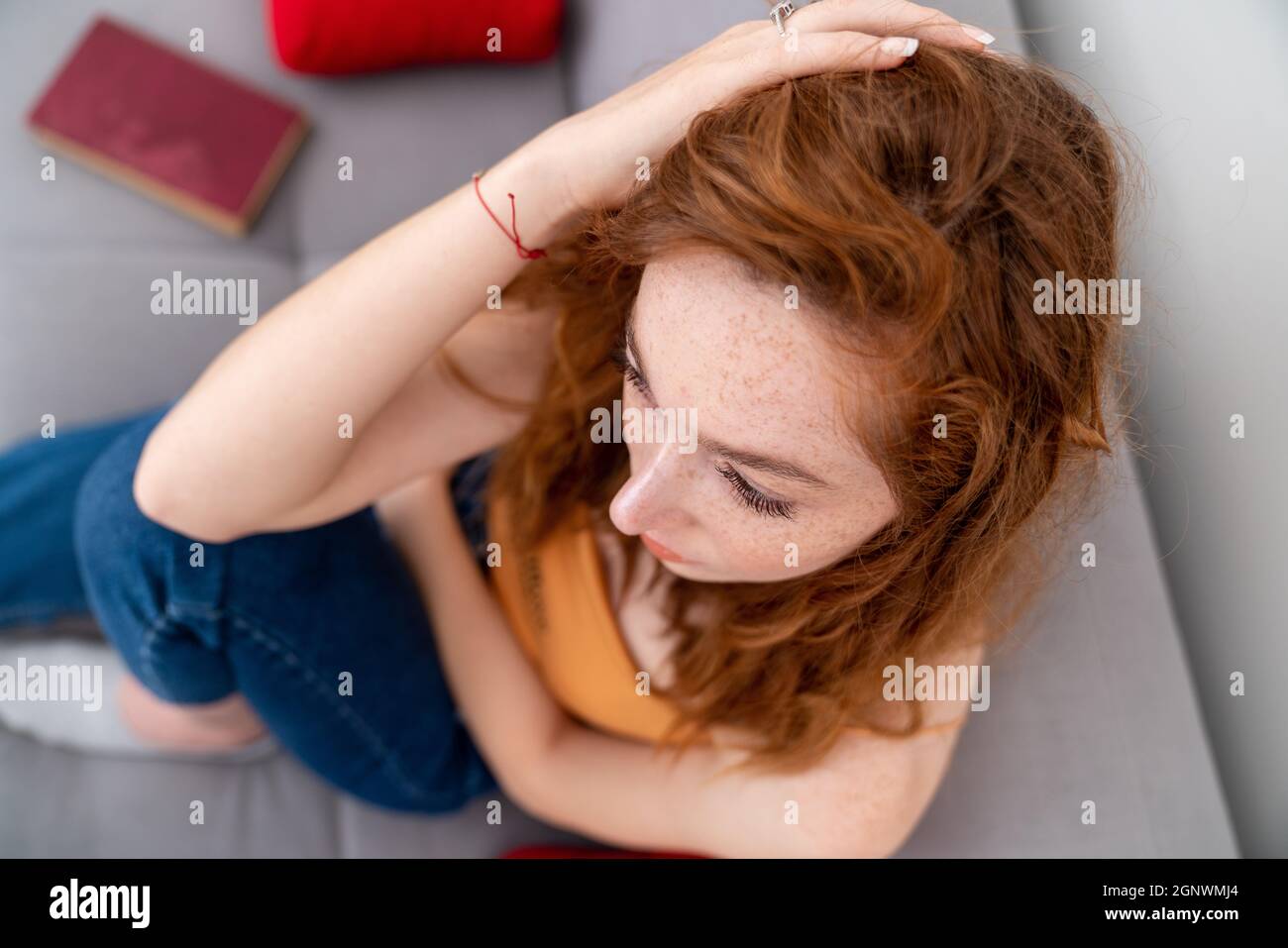Triste giovane donna è seduta sul couach ha messo la sua mano sulla sua testa mentre lei pensa. . Foto di alta qualità Foto Stock