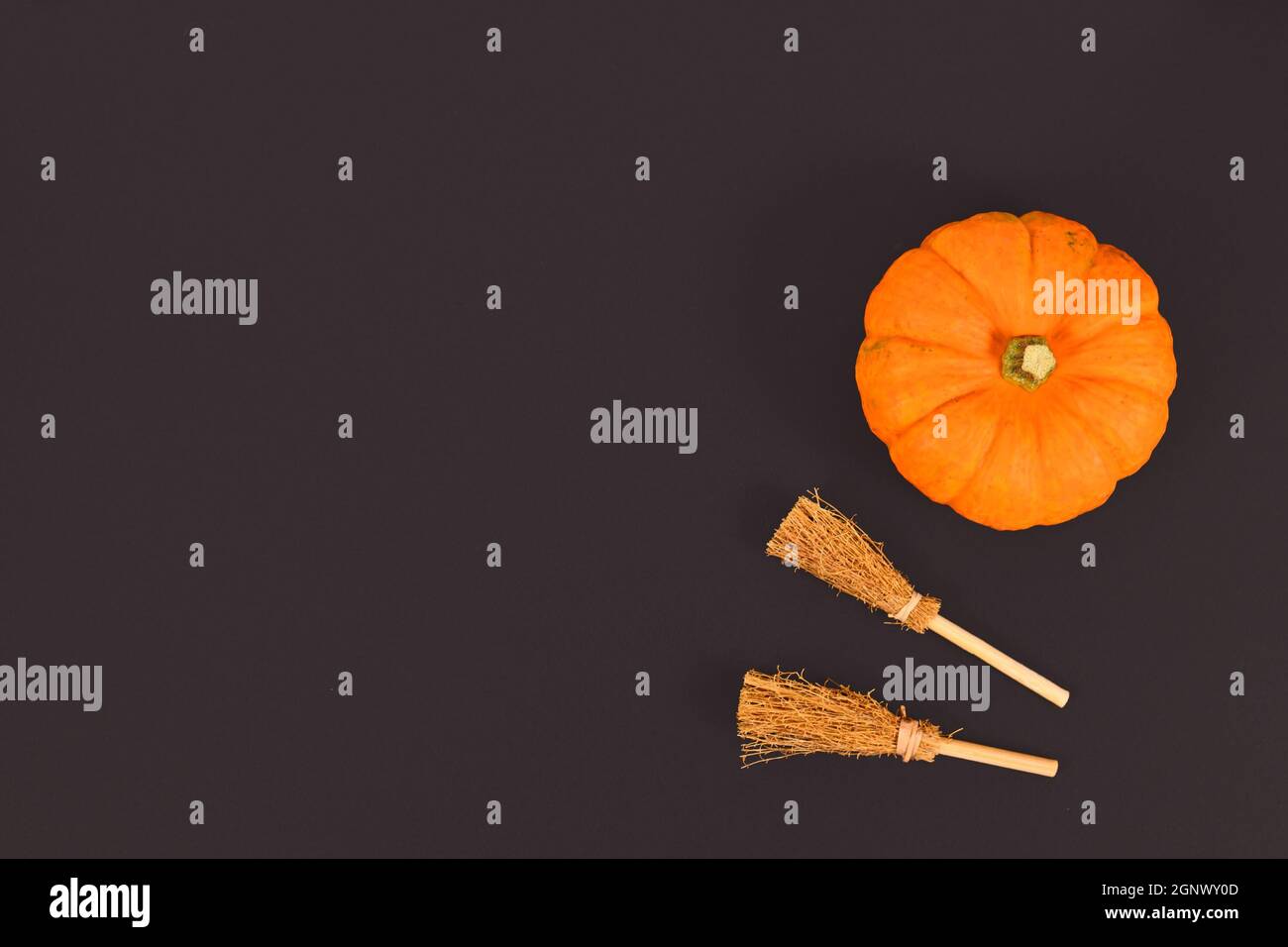 Zucca arancione di Halloween e scopa per streghe in un angolo di sfondo nero con spazio copia Foto Stock
