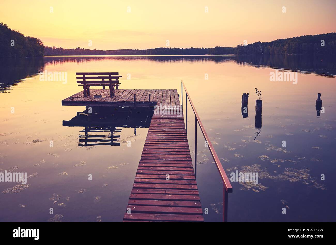 Molo lago in legno con panca al tramonto, tonificante applicato. Foto Stock