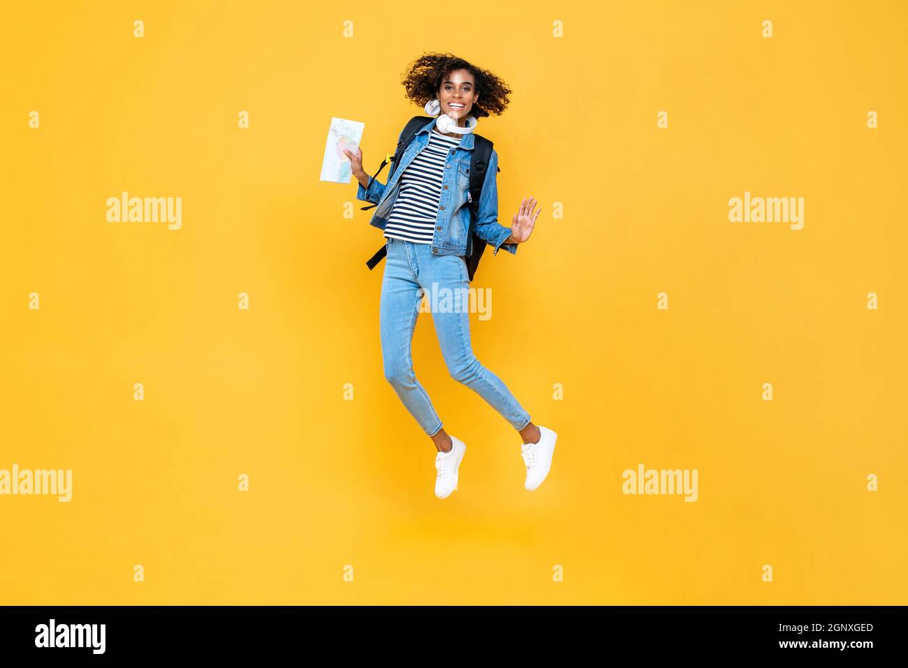 Felice energico sorridente giovane donna turistica tenendo mappa salto isolato su sfondo giallo studio Foto Stock