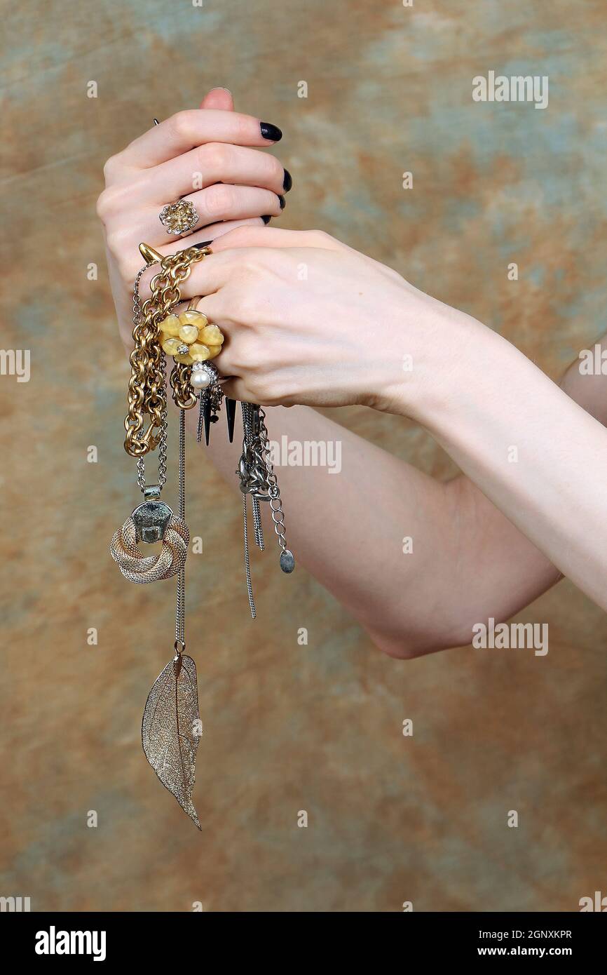 Mani femminili che tengono il palo dei monili costosi dell'oro con gli  anelli e collane Foto stock - Alamy