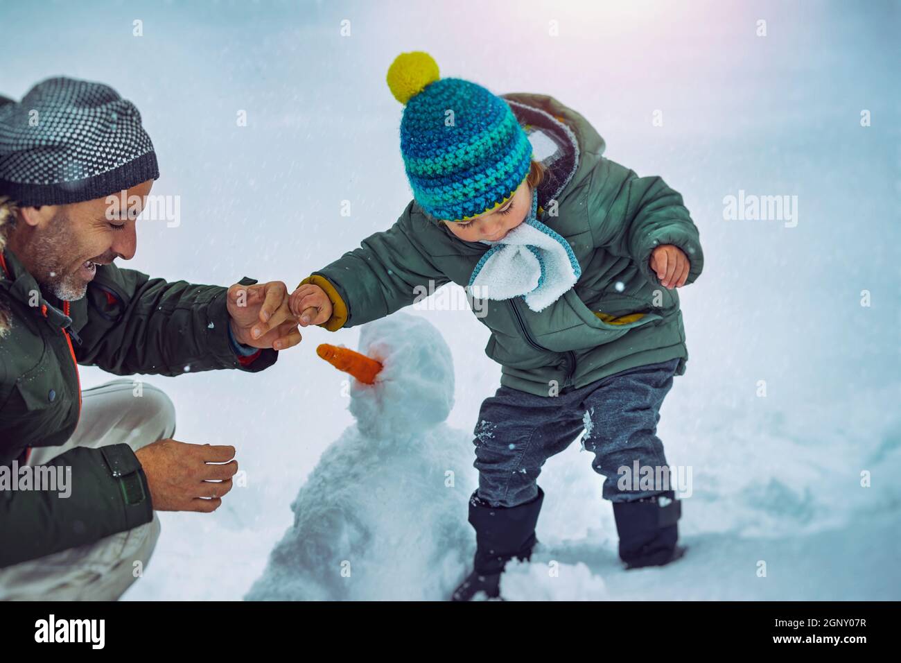 Padre e piccolo Figlio costruendo un pupazzo di neve nel Parco Snowy. Godendo del tempo insieme all'aperto. Gioia invernale tradizionale. Buone feste di Natale. Foto Stock