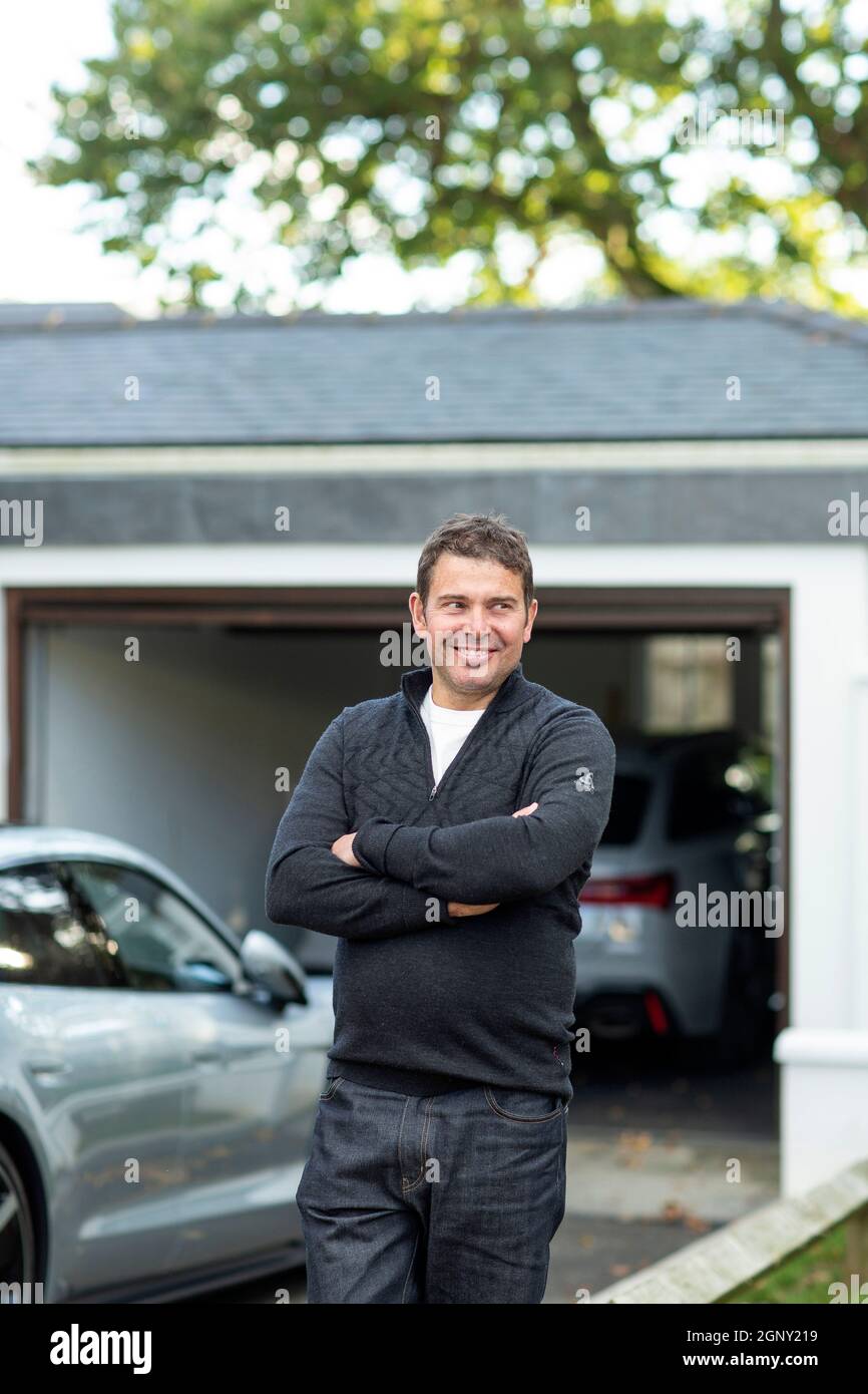 maschio con le sue auto elettriche di fronte al suo garage casa Foto Stock