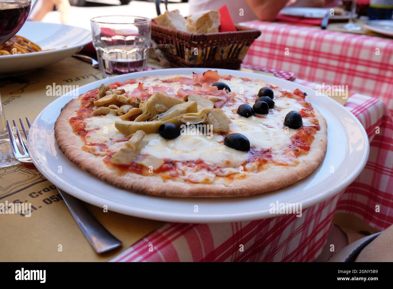 Una classica pizza quattro stagioni servita all'aperto in un ristorante pizzeria a Lucca Foto Stock
