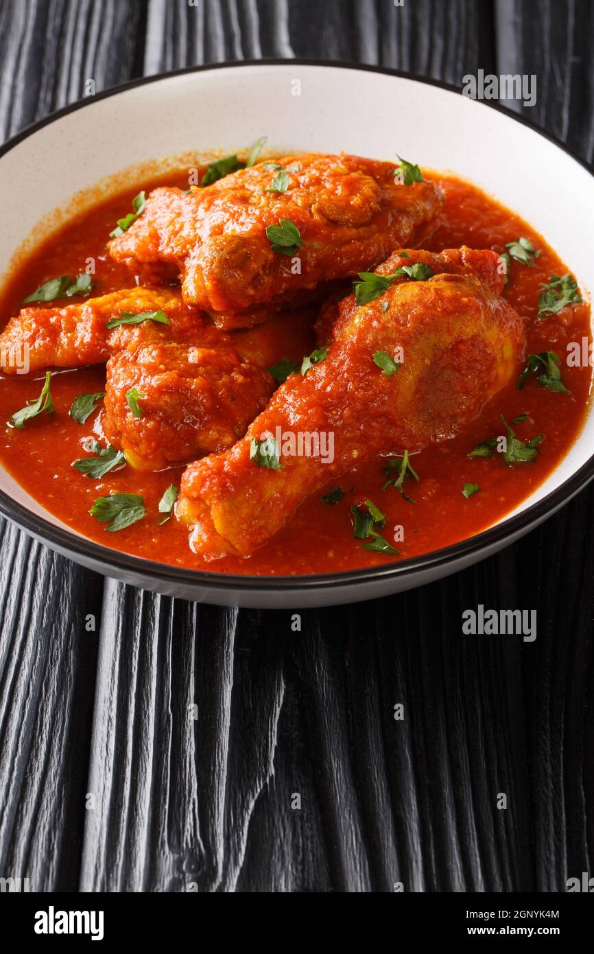 Ayam masak merah è un piatto tradizionale malese è una casseruola di pezzi di pollo in peperoncino sambal secco primo piano in una ciotola sul tavolo. Vertica Foto Stock