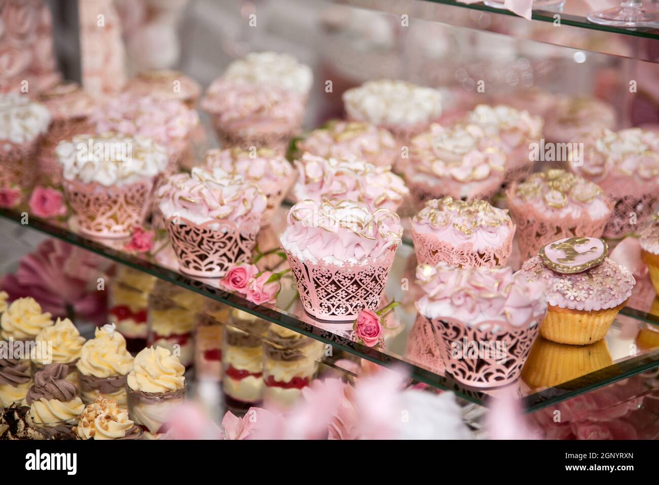 Deliziosi dessert al bar delle caramelle per matrimoni nell'area buffet: Muffin decorati con angeli, rosette di zucchero e tinture d'oro. Foto Stock