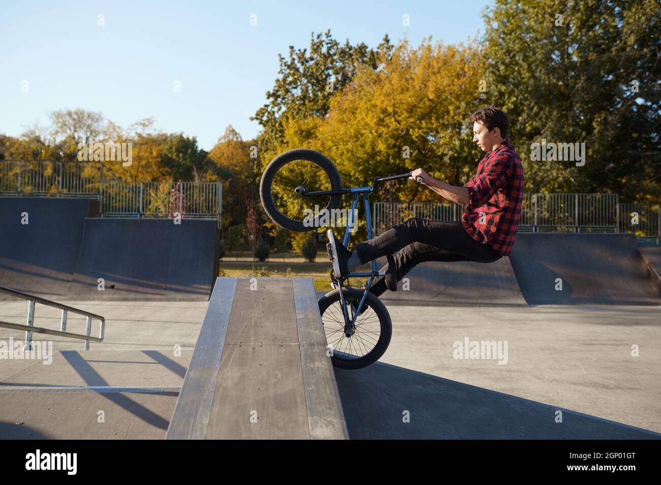 Il giovane biker maschio Bmx salta sul muro nello skatepark. Sport estremi in bicicletta, pericoloso trick in bicicletta, passeggiate in strada, ciclismo nel parco estivo Foto Stock