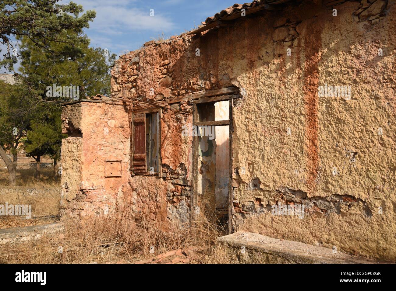 Paesaggio con vista panoramica di una vecchia casa rurale abbandonata facciata con un muro di pietra argillosa e porte e finestre in legno antico in Attica, Grecia. Foto Stock