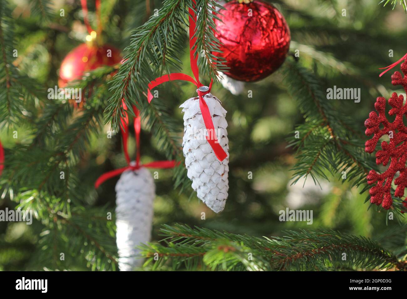 Decorazione di Natale su sfondo verde. Pinecones sul ramo dell'abete con palle di Natale, decorazioni . Foto Stock