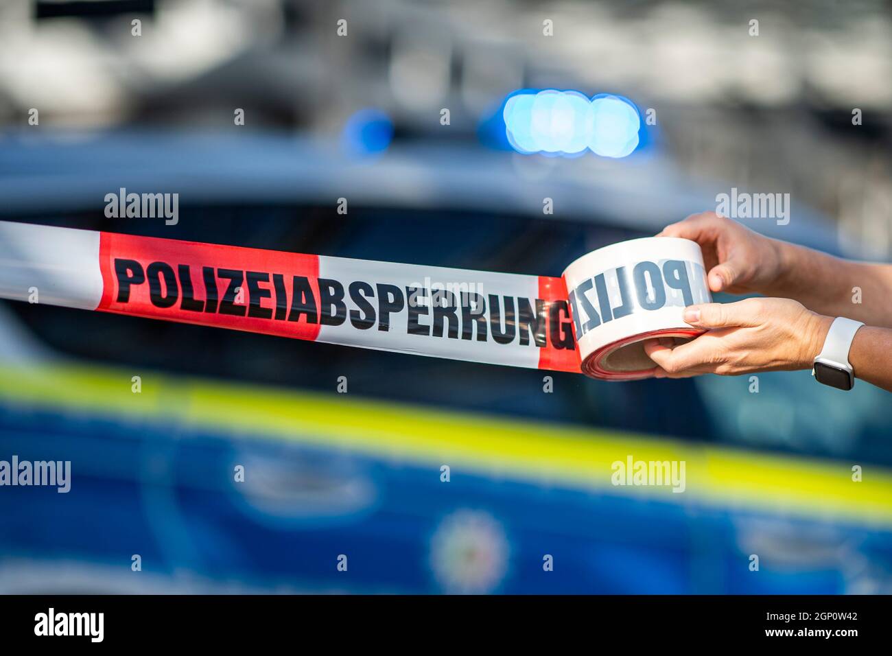ILLUSTRAZIONE - 28 settembre 2021, Renania settentrionale-Vestfalia, Gütersloh: Un nastro di barriera è arrotolato davanti ad un'auto di polizia con la luce blu su di esso. Foto: David Inderlied/dpa Foto Stock