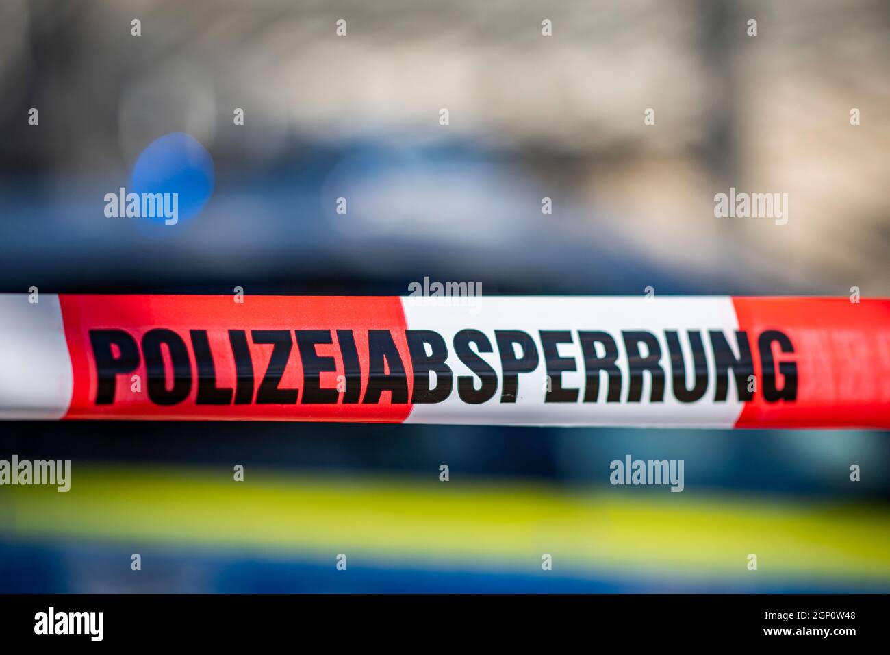 ILLUSTRAZIONE - 28 settembre 2021, Renania settentrionale-Vestfalia, Gütersloh: Un nastro di barriera con l'iscrizione 'barriera di polizia' è teso di fronte ad una macchina di polizia. Foto: David Inderlied/dpa Foto Stock