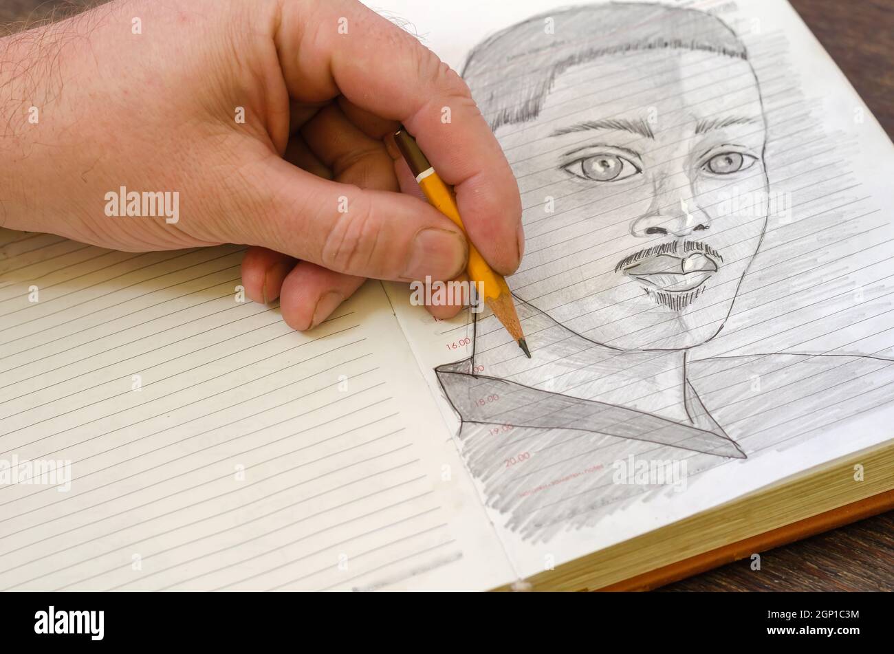 L'uomo disegna un disegno a matita di un giovane maschio adulto in un diario aperto Foto Stock