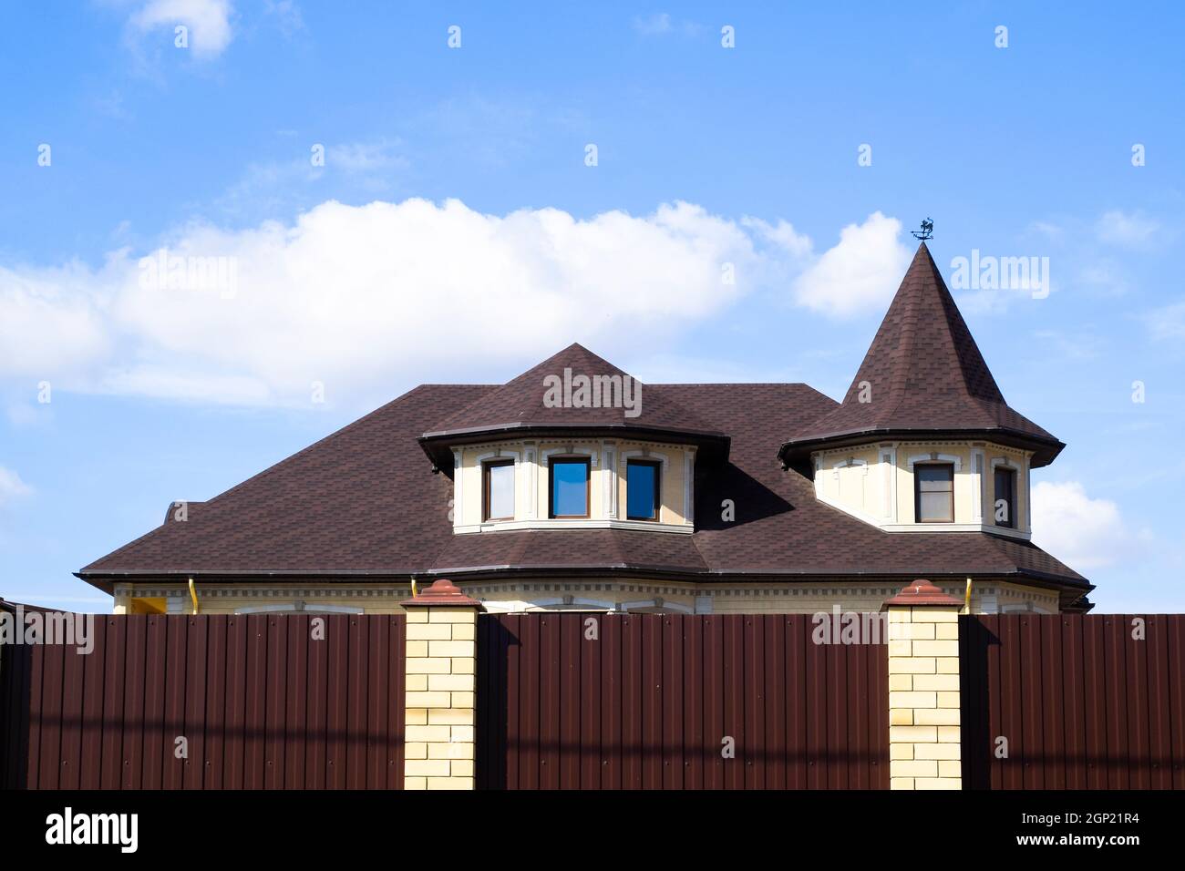 Metallo decorativi sul tetto di una casa di mattoni. Recinzione fatta di metallo ondulato Foto Stock