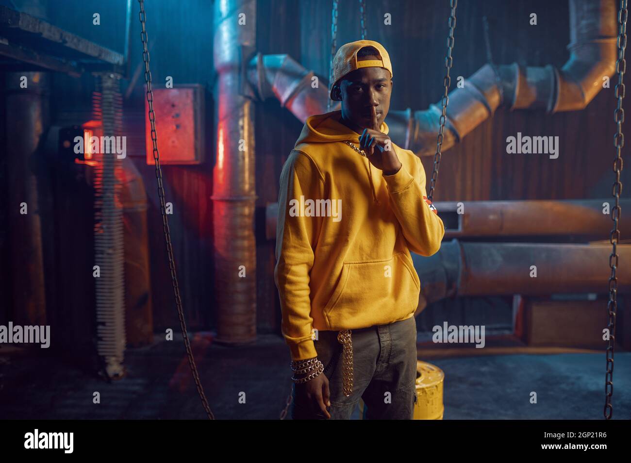 Elegante rapper in felpa con cappuccio gialla e cappellino da baseball in studio con decorazione sotterranea. Artista hip hop cantante rap break dance Foto stock Alamy