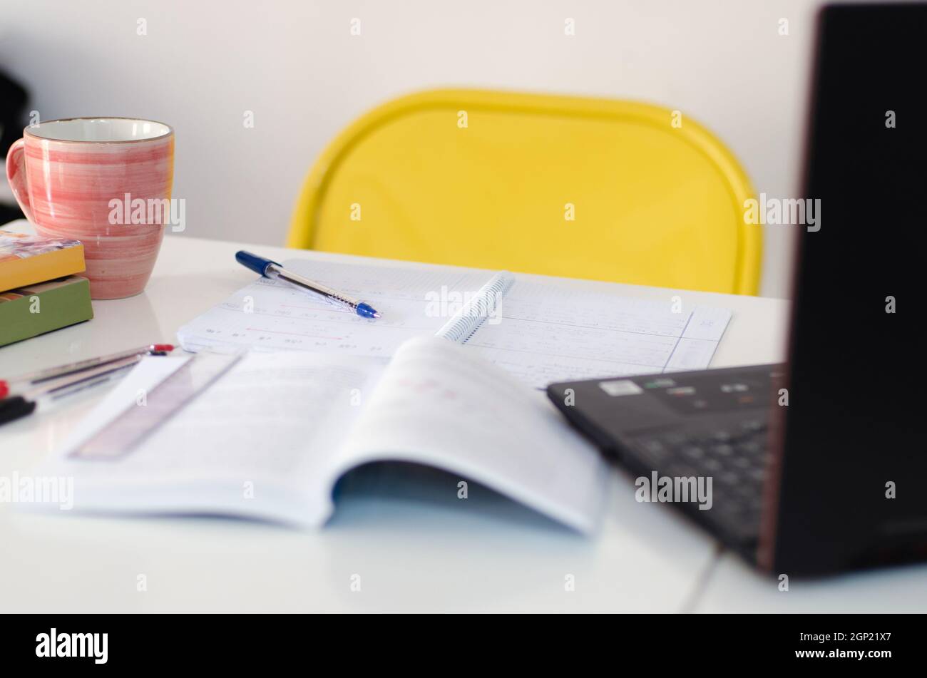 scrivania per studenti con libri, penne e computer. scrivania per uomo d'affari con laptop e materiali da biblioteca. spazio per copie su una parete bianca vuota Foto Stock