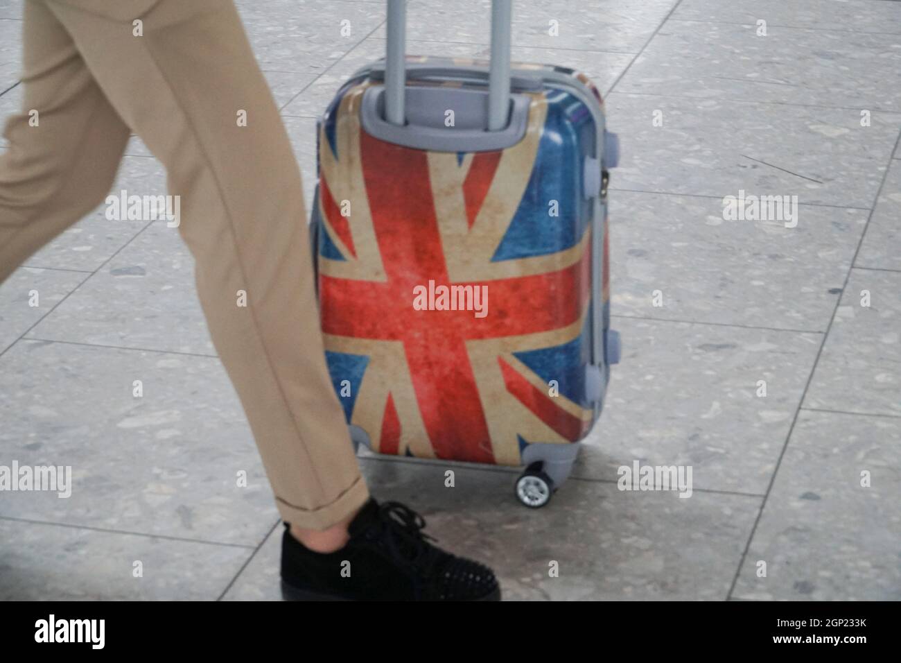 Londra, Regno Unito, 28 settembre 2021: Al terminal 5 dell'aeroporto di Heathrow un uomo ha spinto una valigia roll-along decorata con la bandiera Union Jack. I viaggiatori in partenza devono rispettare varie misure di sicurezza covide per prevenire la diffusione del coronavirus. Le regole del governo inglese sui test covidi stanno per cambiare, lunedì 4 ottobre, da quando non sarà più necessario che i viaggiatori britannici che sono vaccinati due volte prendano un test covido prima di tornare a casa. Anna Watson/Alamy Live News Foto Stock