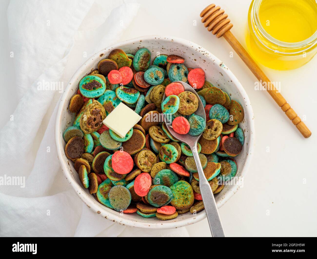 Cibo alla moda - cereali pancake. Un mucchio di mini frittelle di cereali colorate. Minuscoli pancake di colore naturale: Matcha verde, spirulina turchese, pisello blu, re Foto Stock