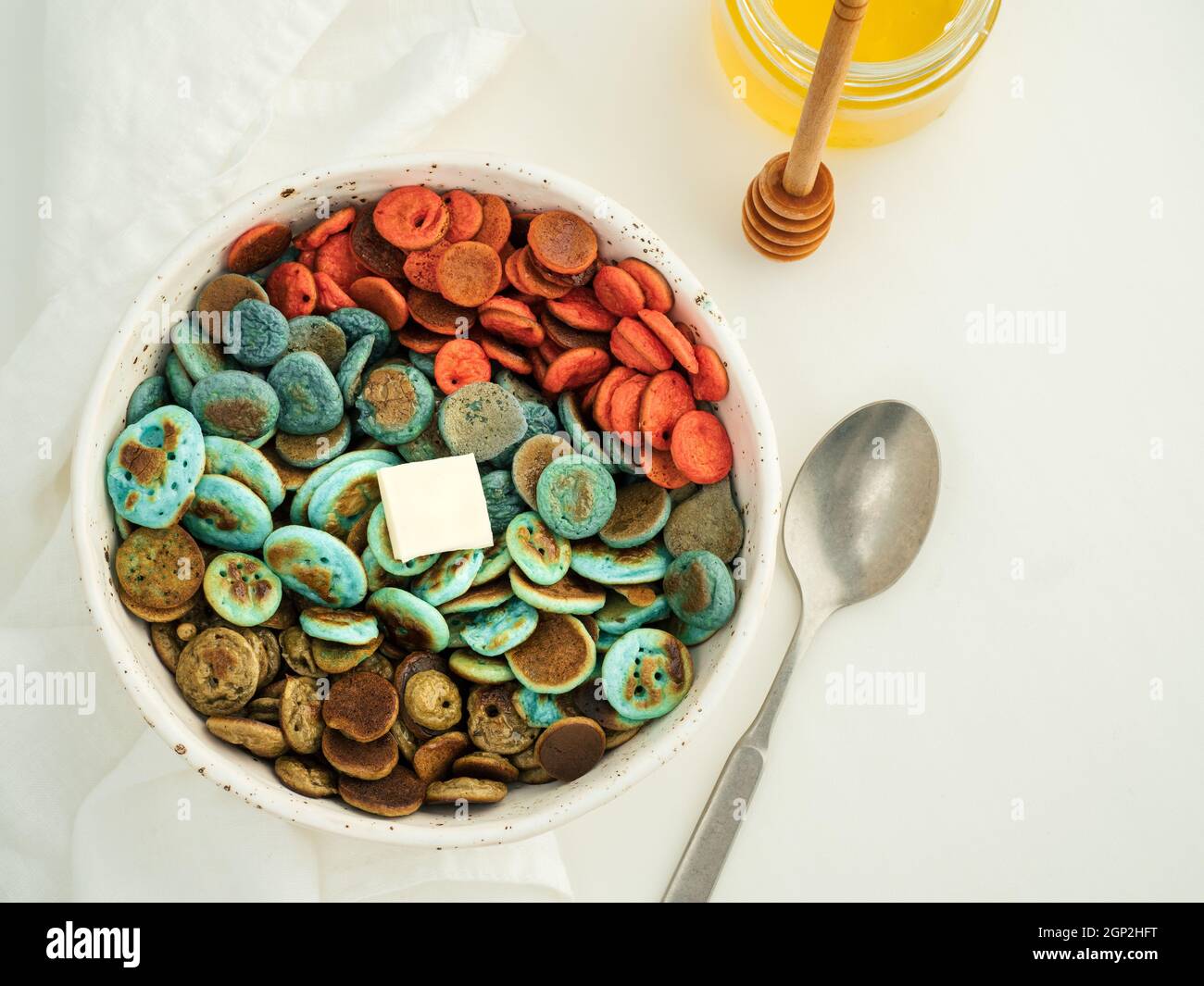 Cibo alla moda - cereali pancake. Un mucchio di mini frittelle di cereali colorate. Minuscoli pancake di colore naturale: Matcha verde, spirulina turchese, pisello blu, re Foto Stock