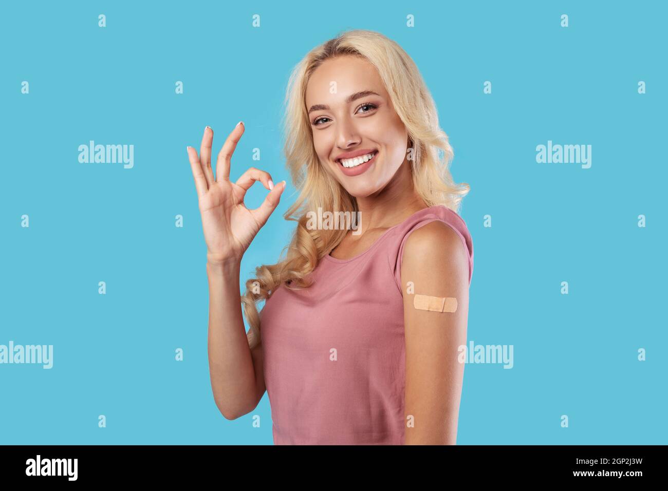Vaccino efficace contro Covid. Ritratto di paziente femmina sorridente allegro che mostra braccio vaccinato con la patch appiccicosa sulla spalla dopo essere stato Foto Stock