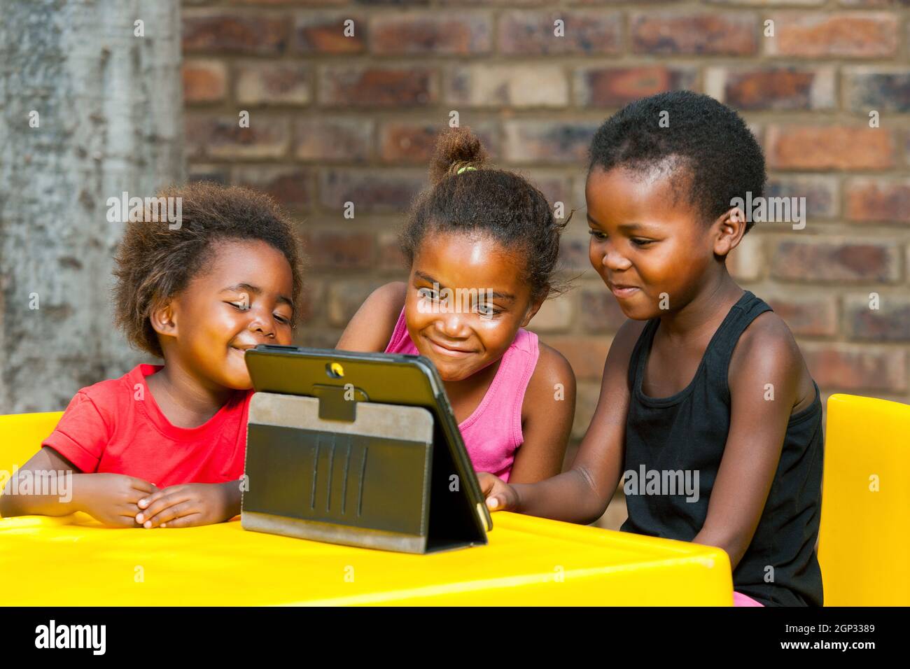 Ritratto di tre ragazze africane che giocano a videogame per il tempo libero su tablet. Foto Stock