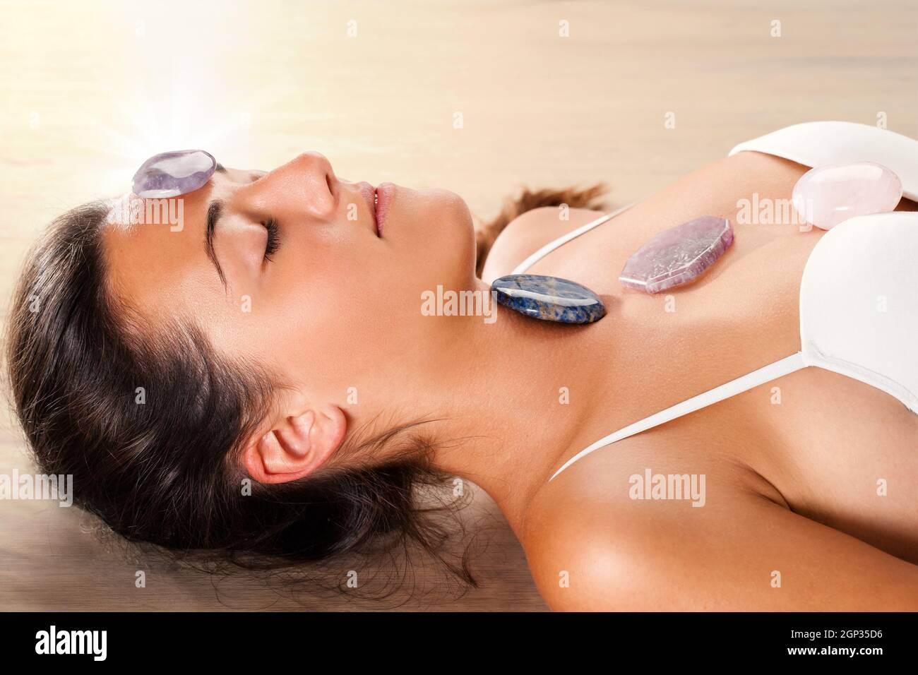 Close up attraente giovane donna meditando con gli occhi chiusi. Gemme preziose sulla sommità della fronte e petto. Foto Stock