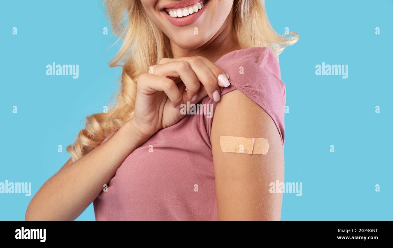 Vaccinazione per la protezione durante il Global Covid-19 Pandemic. Primo piano di paziente felice femmina mostrando braccio con cerotto dopo l'iniezione di vaccino Foto Stock