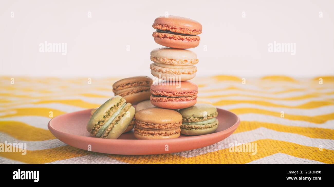 La torre dei macaroni sul piatto da dessert a casa. Maccheroni carini sul decoro domestico della tovaglia al tavolo della cucina Foto Stock