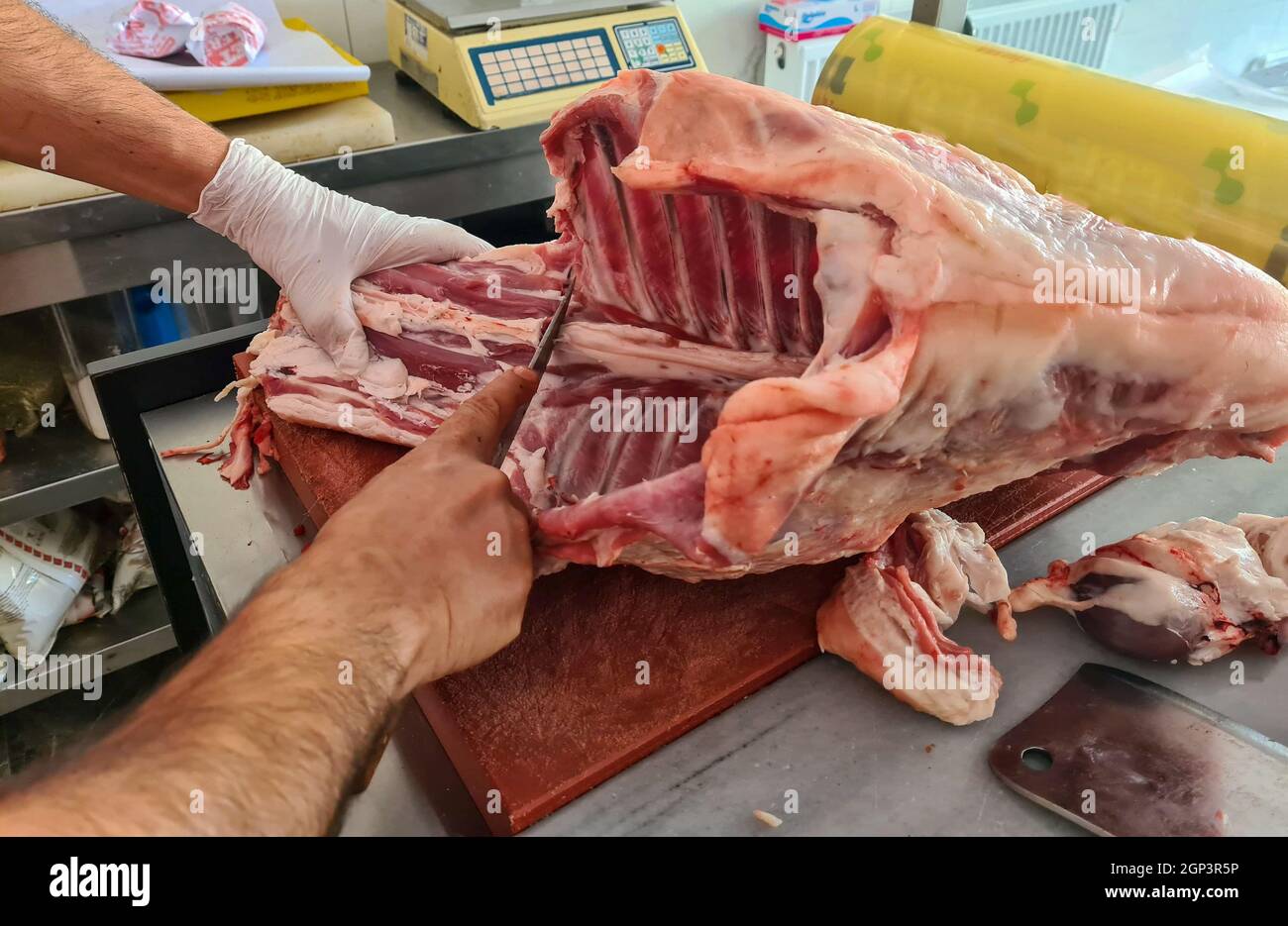 Il macellaio separa l'osso dalla carne con un coltello da macellaio al tavolo. Industria della carne. Foto Stock