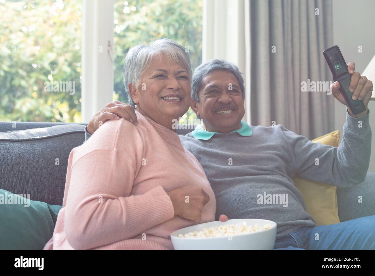 Due diverse coppie anziane sedute sul divano, guardando la tv e divertendosi Foto Stock