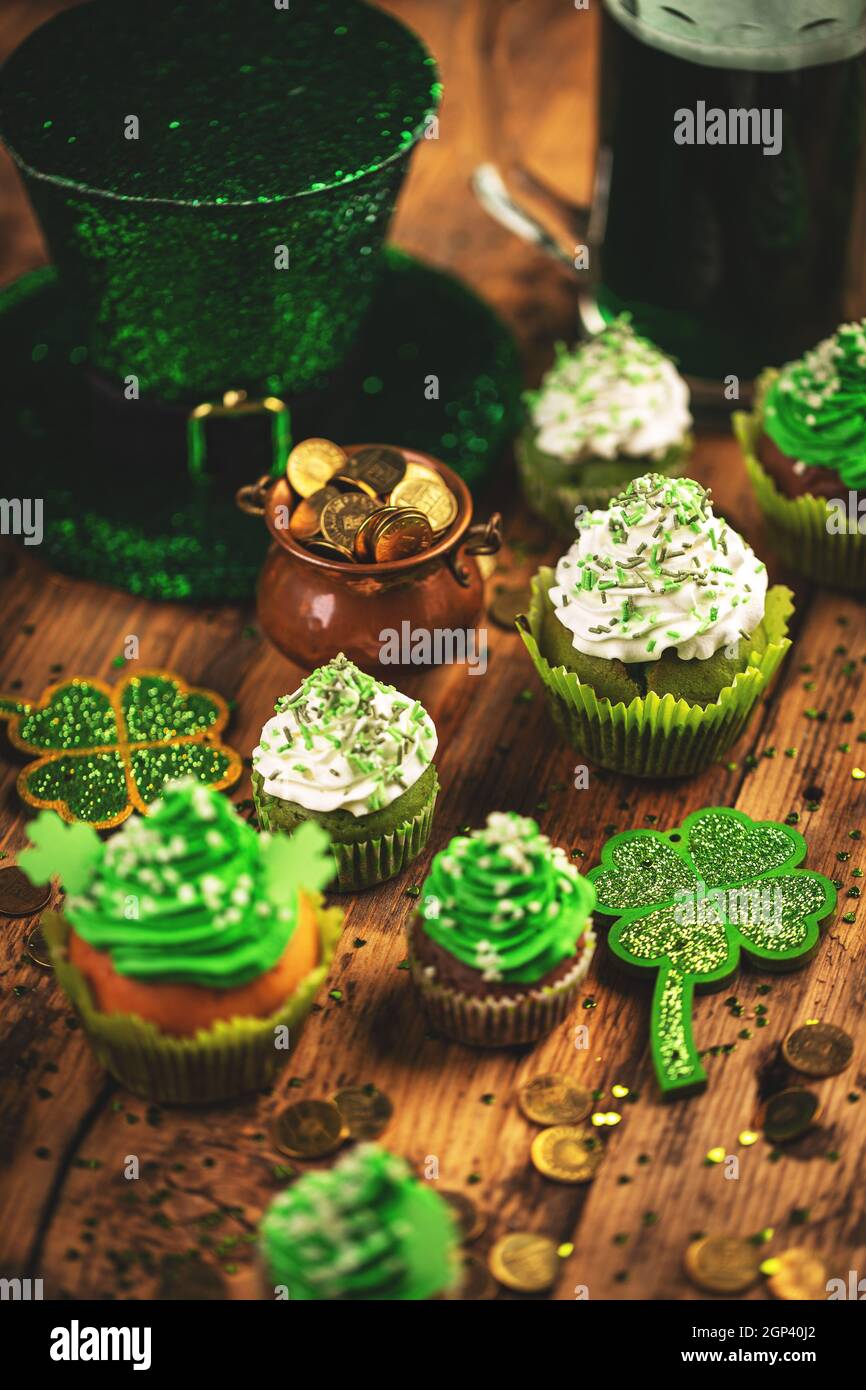 Festa di San Patrizio. Buona fortuna cappello leprechaun, cupcakes e pentola di monete d'oro Foto Stock